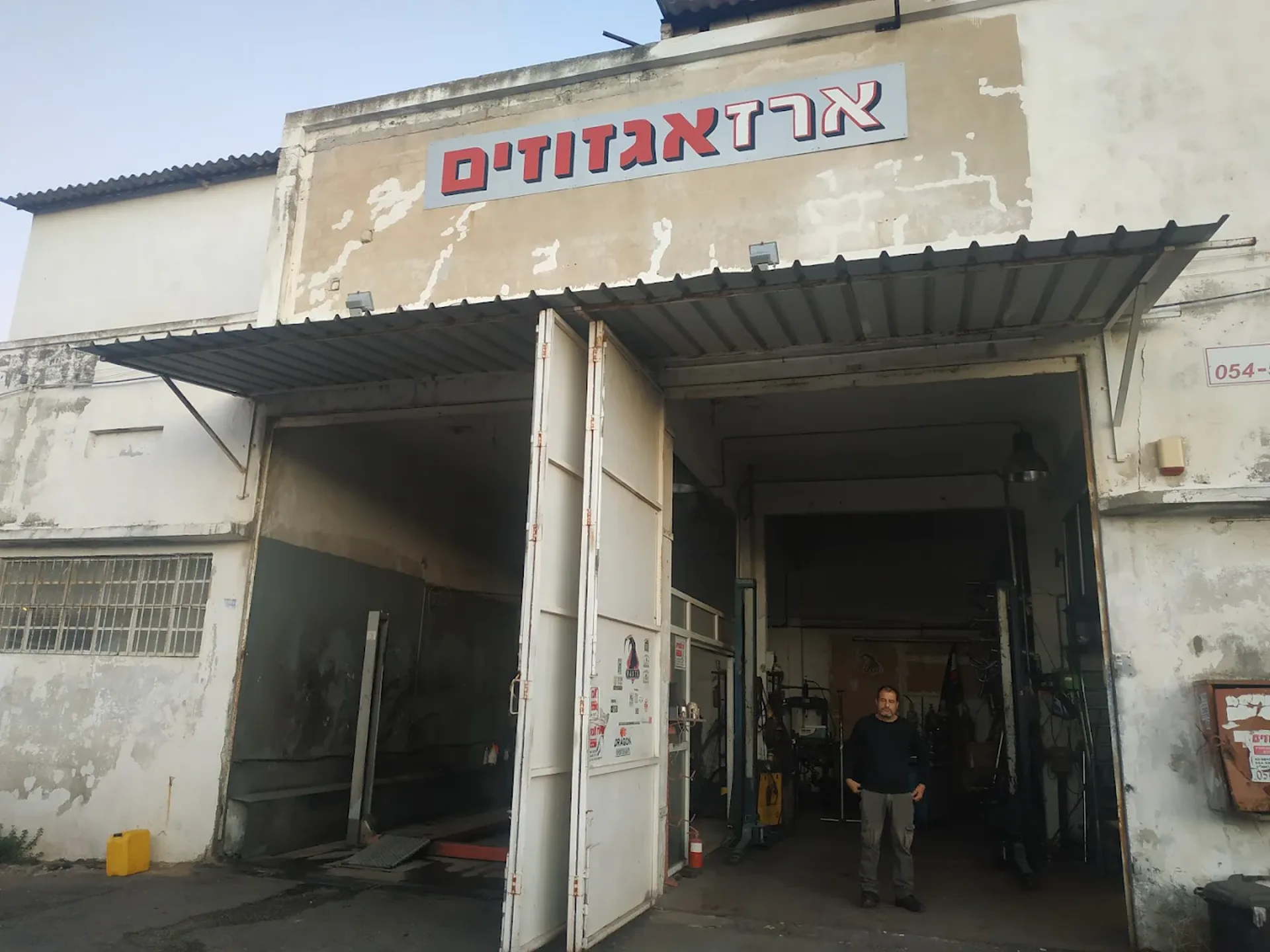 חזית המוסך של ארז אגזוזים — ארז כהן בפתח הסככה